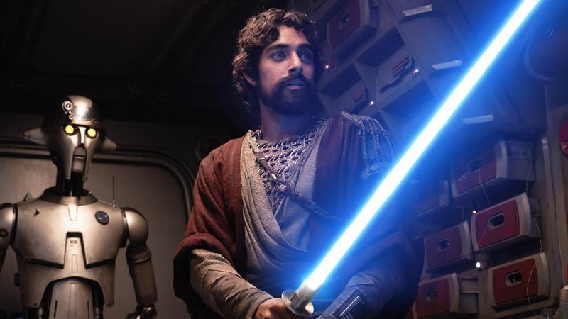 Eman Esfandi wields a blue lightsaber as Ezra Bridger in Ahsoka Season 1 as Huyang looks on.