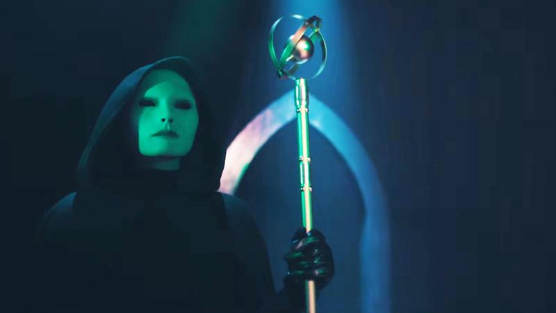 Saturnalia masked hoodie figure with staff.