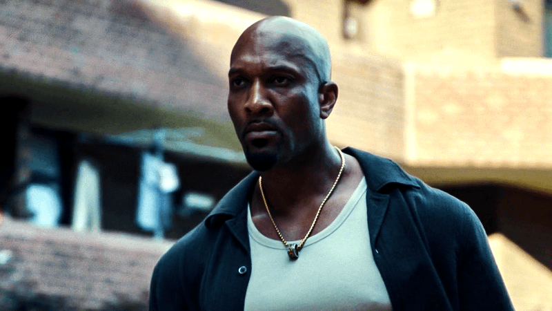 Actor Jamall Johnson wears a blue jacket and a white tank top as Barry, a.k.a. Barracuda, in The Punisher: One Last Kill 