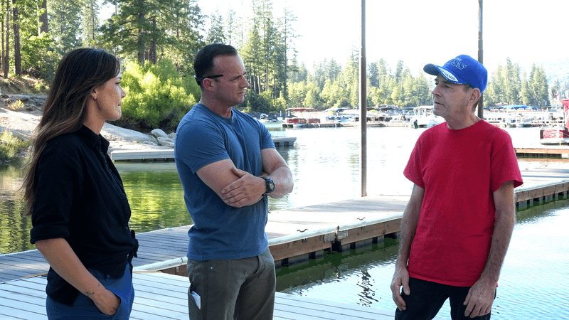 Jessica and Rob standing on a dock talking to someone in a red shirt in Bigfoot Took Her