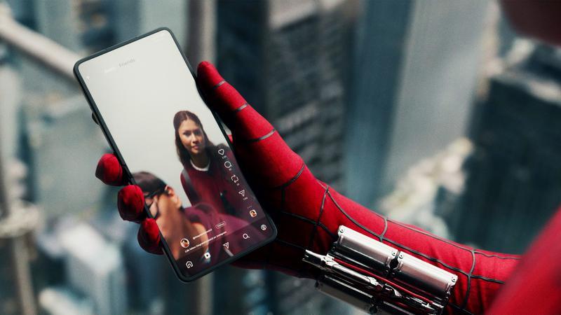 Spider-Man holding his photo that's playing a video of Ned and MJ.