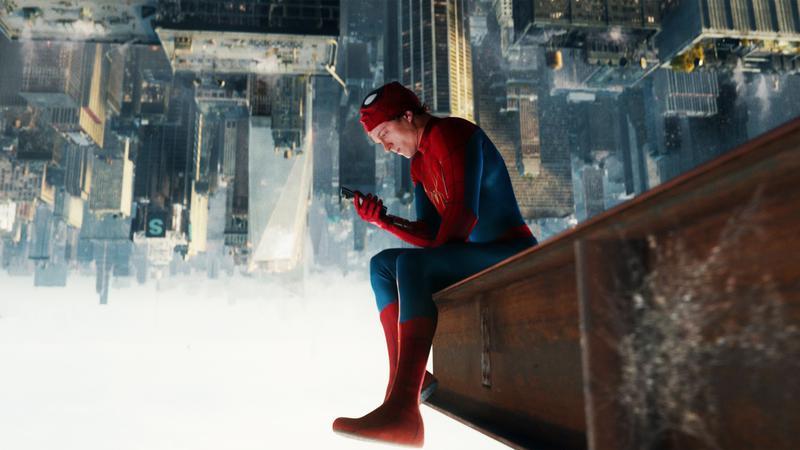 Spider-Man holding his phone sitting upside down.
