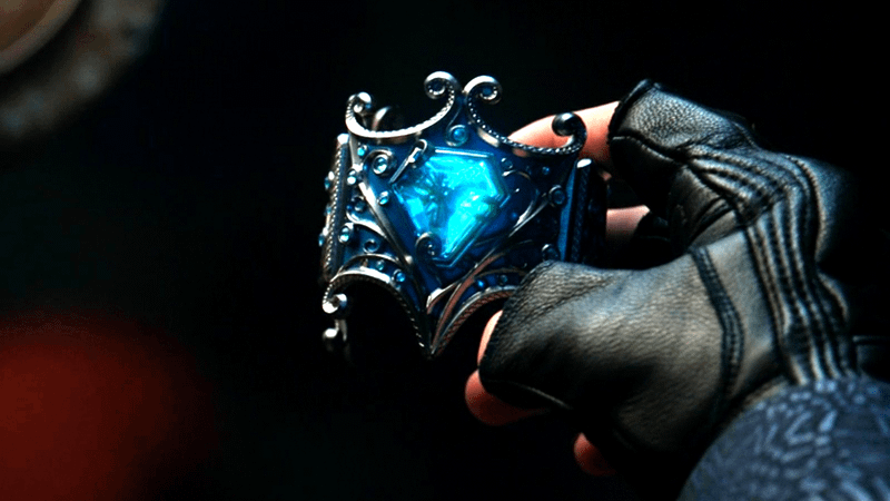 Max Hatter holding a bracelet with a glowing blue gem in it.