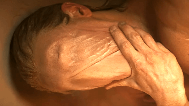 Matt Hagen cradles his face, completely covered by his clay skin in the Clayface teaser trailer.