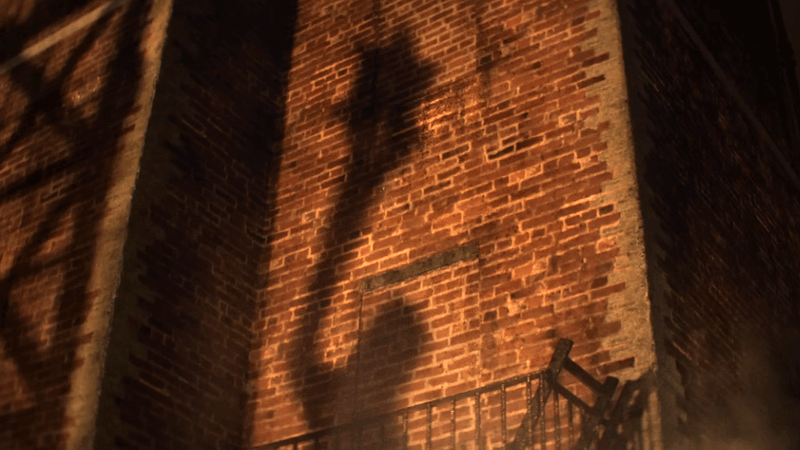 A shadow of Clayface as he shapes his hand into a mace.