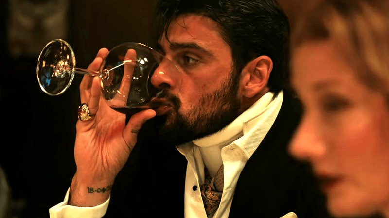 Michele Morrone as Cico drinking wine in The Gentleman Season 2 Episode 1.