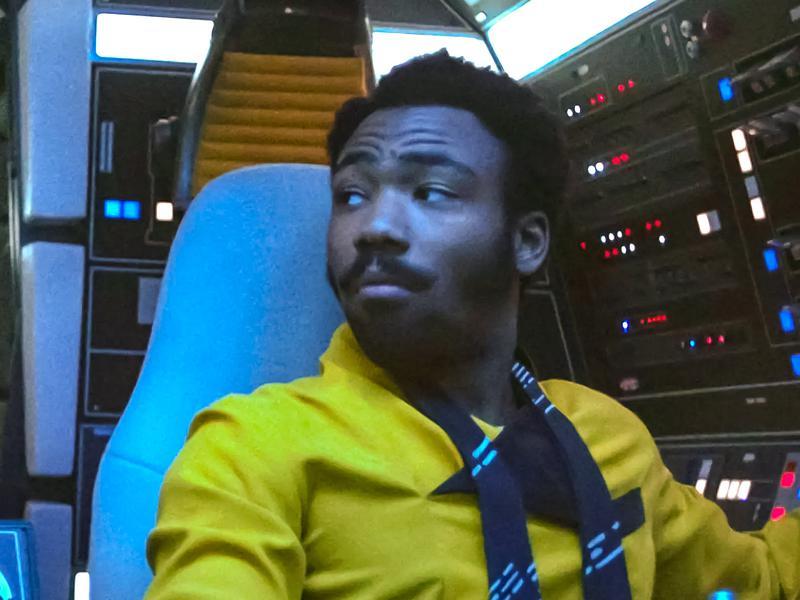 Donald Glover as Lando Calrissian sitting in the cockpit of the Millennium Falcon in Solo: A Star Wars Story