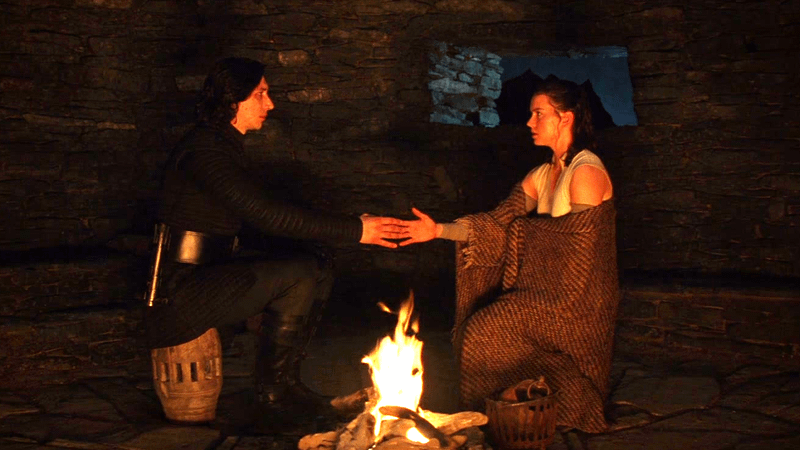 Daisy Ridley as Rey and Adam Driver as Kylo Ren sitting next to each other in The Last Jedi