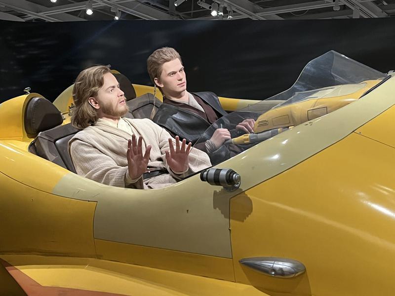 Life-size model of Obi-Wan Kenobi and Anakin Skywalker flying in yellow vehicle from 'Star Wars: Episode II — Attack of the Clones.'