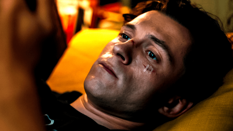 Tom Holland lying in bed and holding his phone.