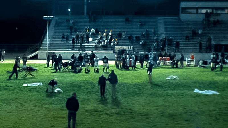 football game, fans, and ambulance workers with stretchers in 'Lanterns' trailer.