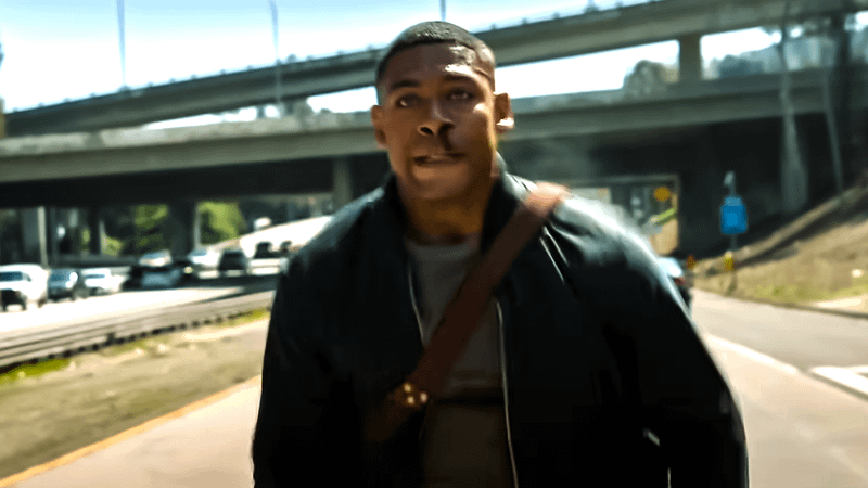 Aaron Pierre as John Stewart covered in blood and walking down a freeway in Lanterns.