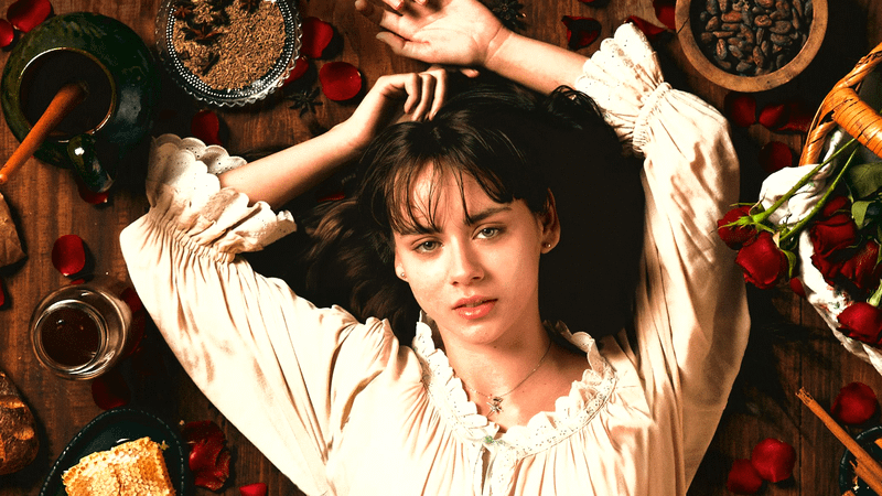 Irene Azula as Tita laying on a kitchen table in Like Water for Chocolate