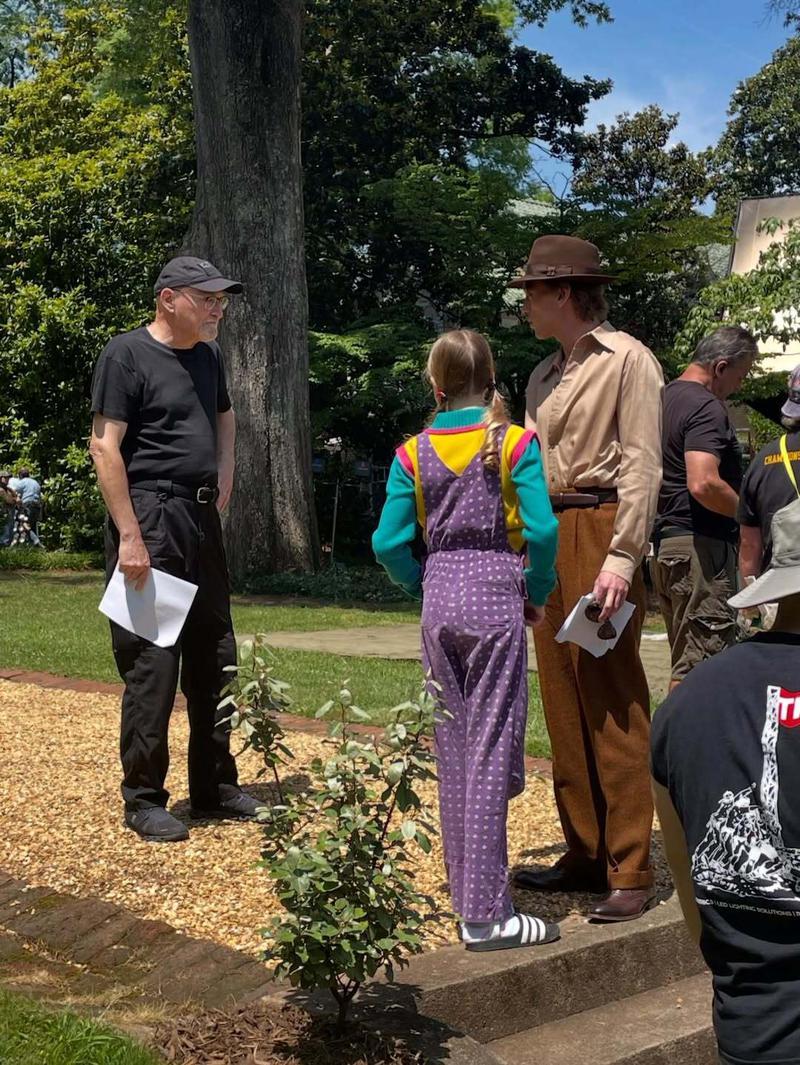 Jamie Campbell Bower and Nell Fisher standing in a park on the set of Stranger Things