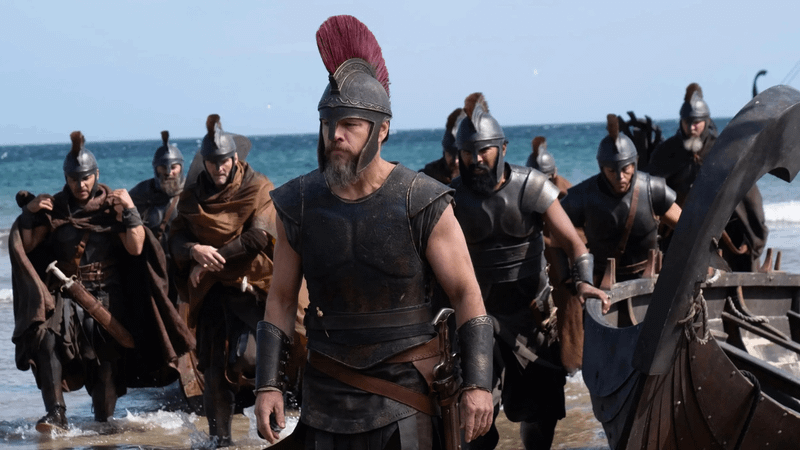 Matt Damon as Odysseus with soldiers on the beach in The Odyssey.