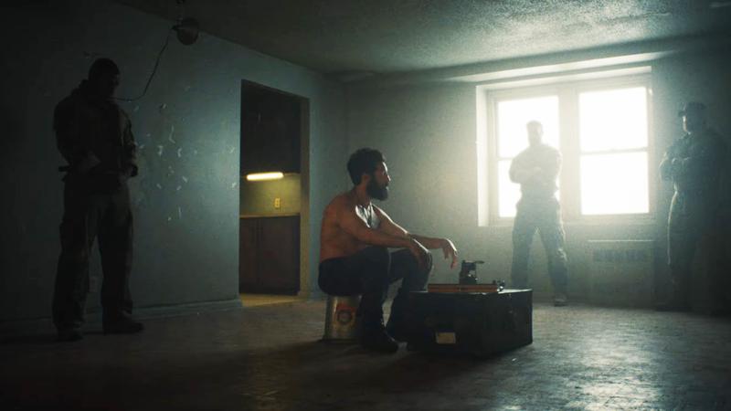 Jon Bernthal as Frank Castle sitting on a bucket surrounded by guards in 'The Punisher: One Last Kill.'