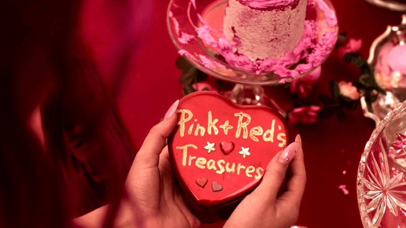 Pink holding a heart-shaped box with text 'Pink + Red's Treasures'.