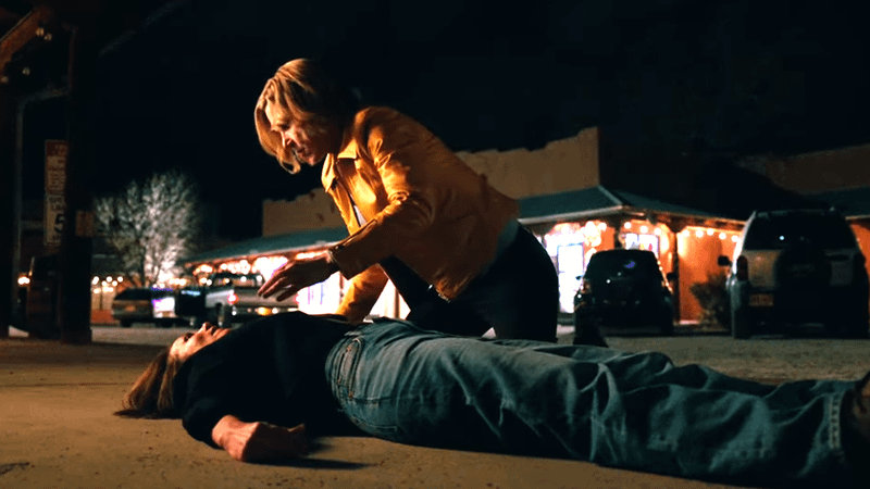 Rhea Seehorn looking over Miriam Shor as Helen as she lay upon the ground outside a bar in Pluribus