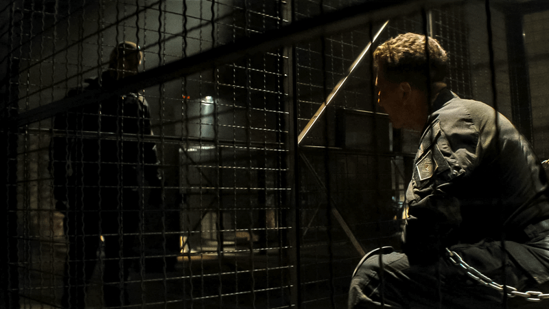 Jon Bernthal as Frank Castle sitting in a cage looking at a shadowy figure in Daredevil: Born Again.