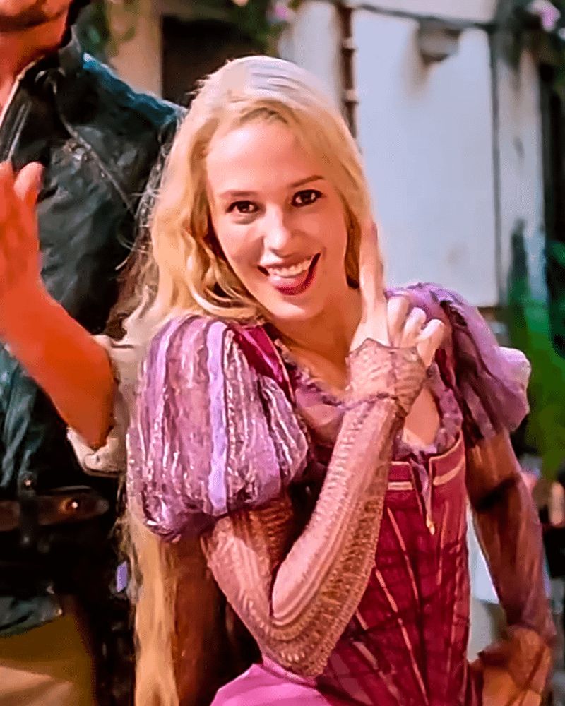 Teagan Croft pointing upward and sticking her tongue out in her Rapunzel costume.