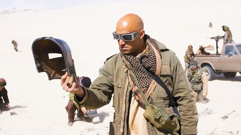 Raza holding Iron Man mask in dessert with Ten Rings soldiers.