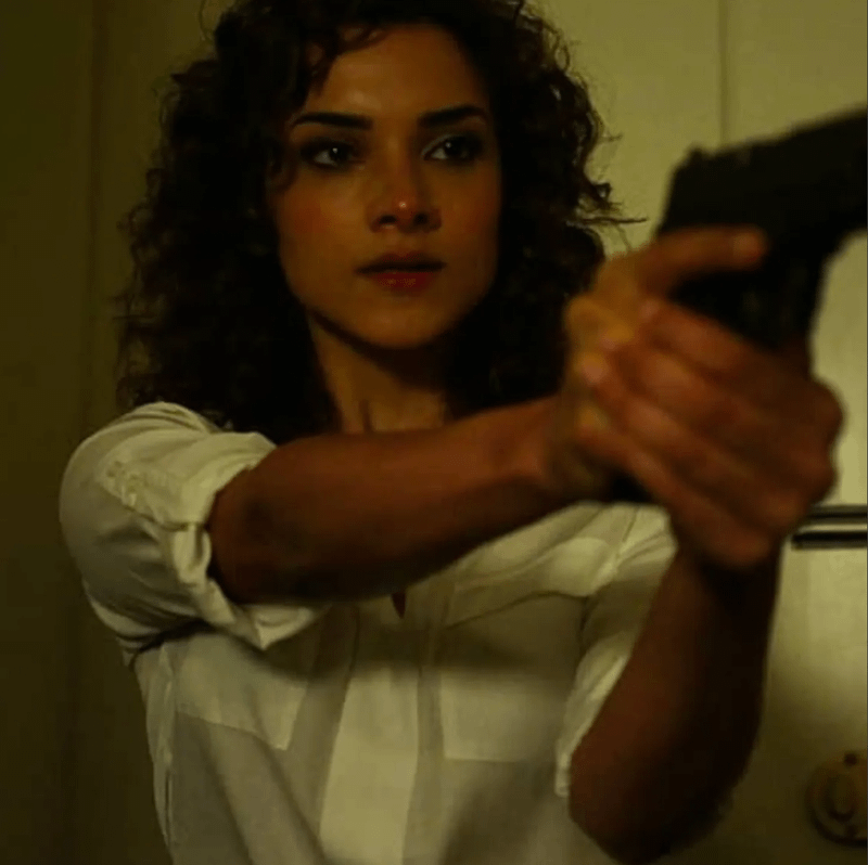 Dinah Madani wielding a gun as she battles with Krista Dumont.
