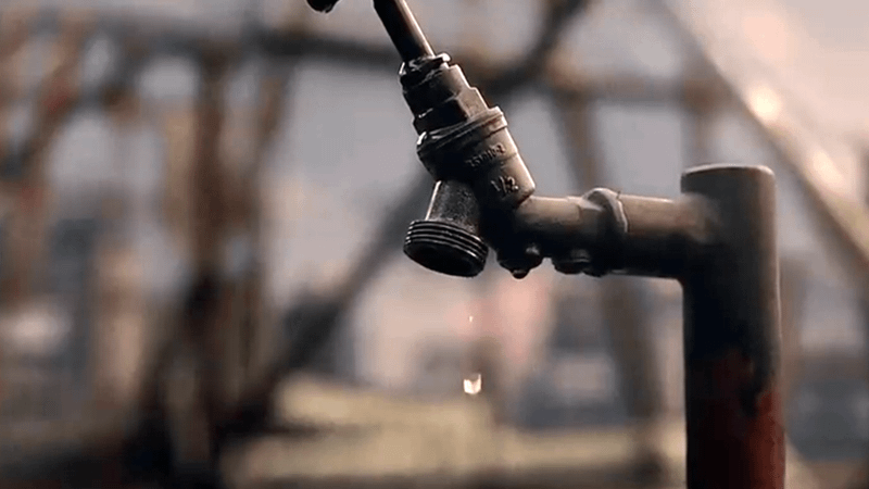 A water droplet falling from a spigot.