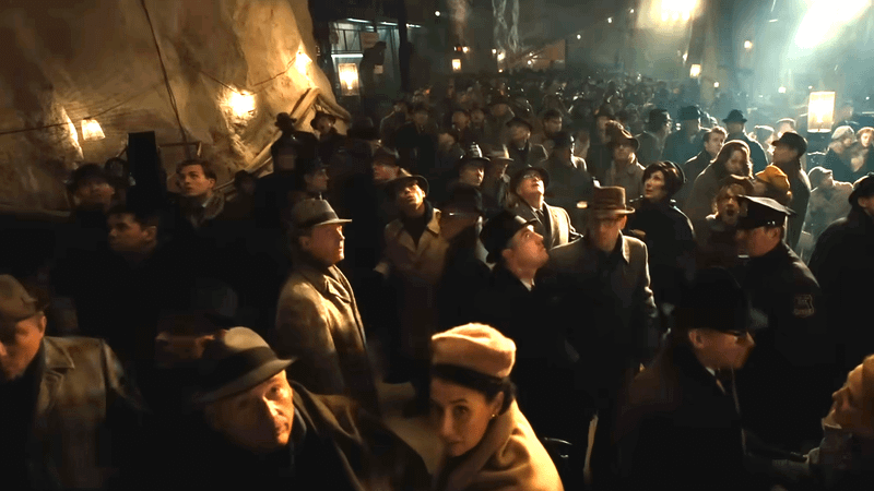 A crowd of people in what looks like a sandy, underground, cave-like location in the official trailer for 