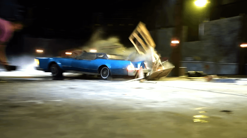 Blue car smashing into crates in garage