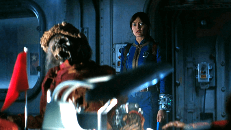 Ella Purnell as Lucy looking shocked in front of a skeleton in Vault 24 in Fallout