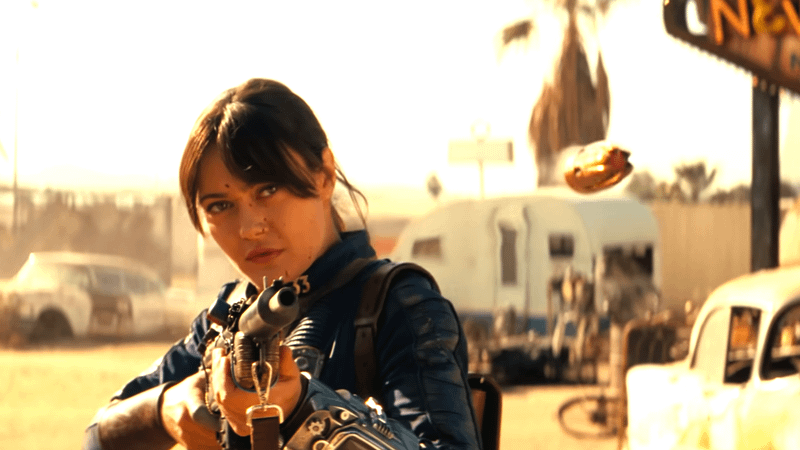 Ella Purnell as Lucy shooting a gun in a desert town in Fallout Season 2